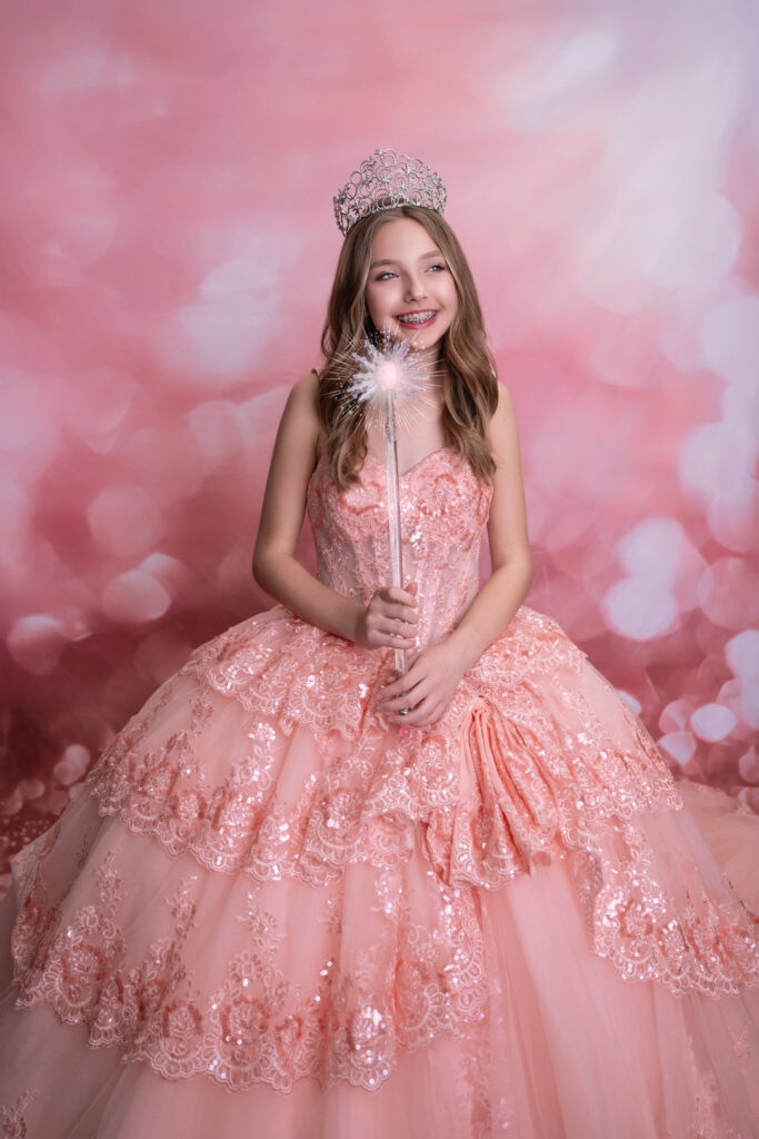 Whimsical portrait of a tween model in a Glinda inspired gown and sparkling tiara, holding a magic wand. Captured by MuSen Photos, this fine art photography session in New Jersey highlights fairy-tale elegance, perfect for children and teen luxury portraits.